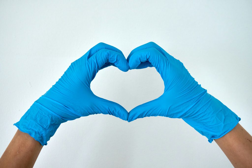 Hände in blauen Handschuhen formen ein Herz